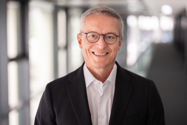 Dr. Karsten Wildberger, Federal Minister for Digital and Administrative Modernization, smiling with glasses in front of blurred background.