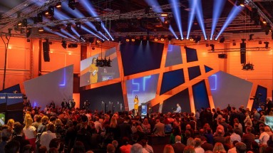 Moderator stands on stage in front of audience at Smart Country Convention