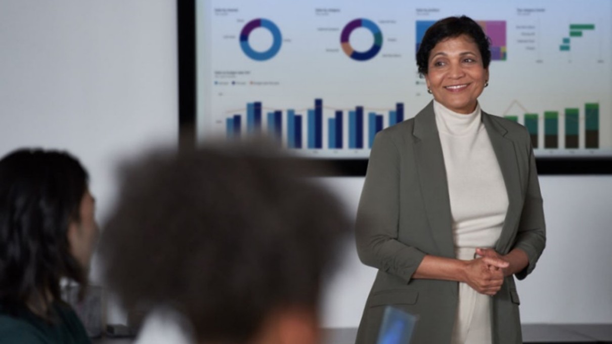 Woman giving a presentation with diagrams, audience in the foreground