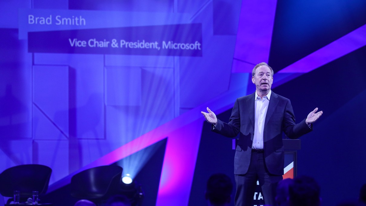 Brad Smith von Microsoft steht auf der SCCON-Bühne, blauer Hintergrund.