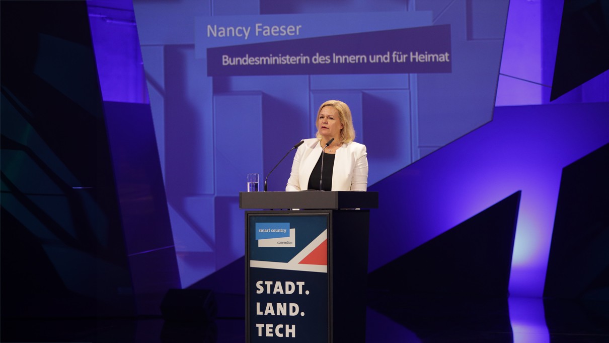Nancy Faeser, Bundesministerin des Innern und für Heimat steht auf der SCCON-Bühne hinter einem Rednerpult, blauer Hintergrund.