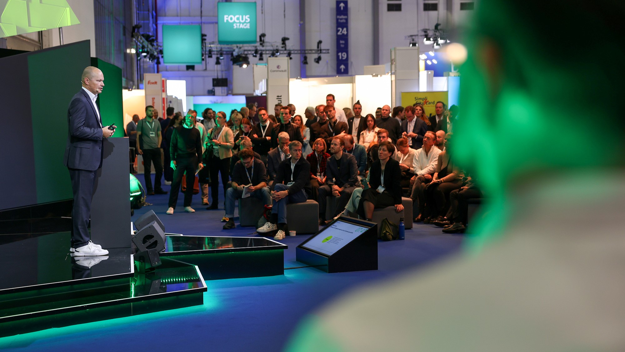 On the left a speaker on a stage, on the right an audience