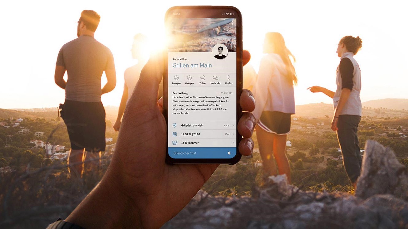 The image shows a group of people in front of a sunset, one hand holding a smartphone on which the Community app is open.
