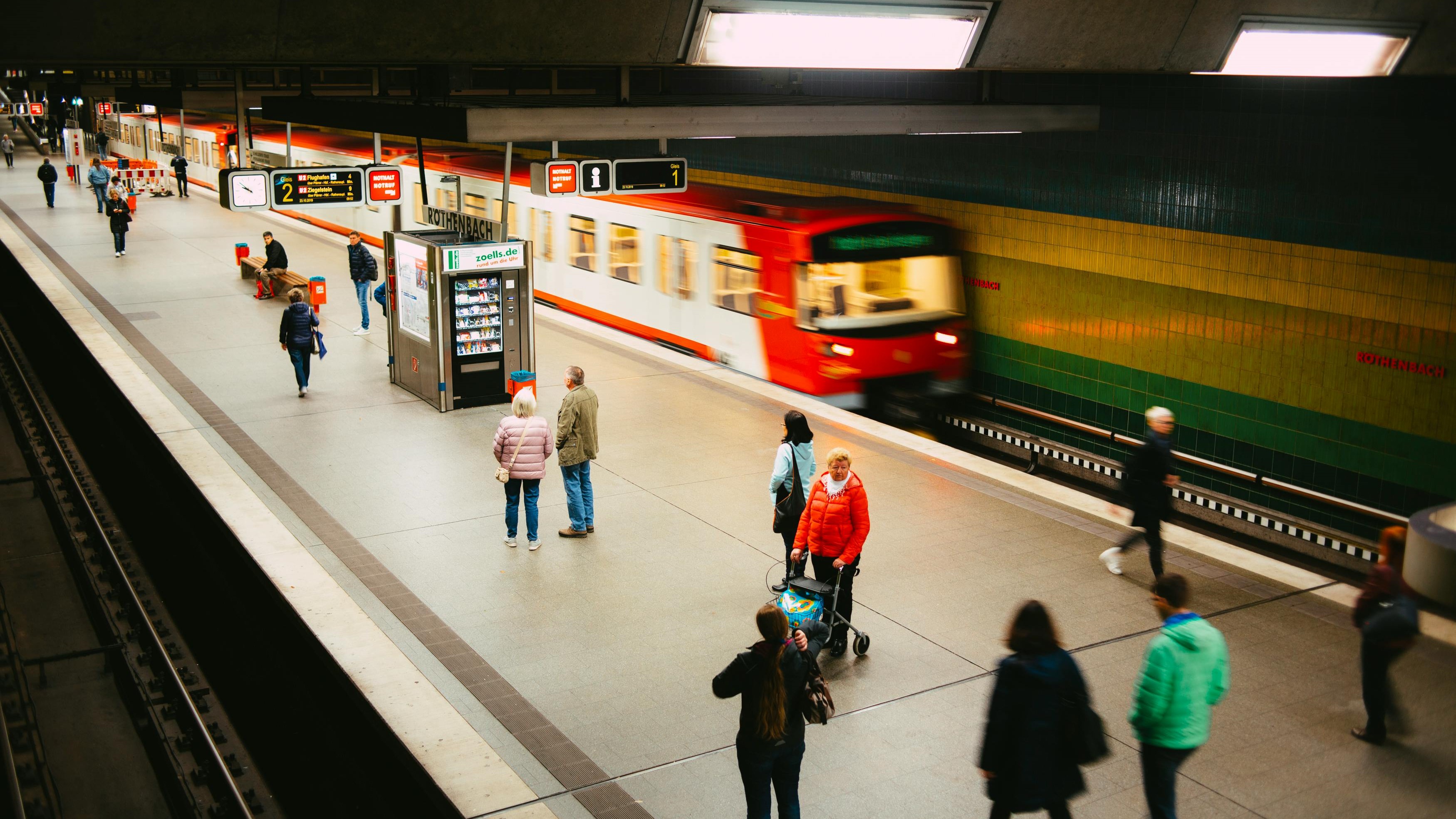 Platform with arriving train, people in the foreground. 