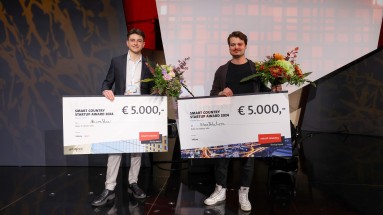 Die Gewinner des Smart Country Startup Awards 2024 auf der SCCON-Bühne, mit großen Schecks und Blumensträußen.  
