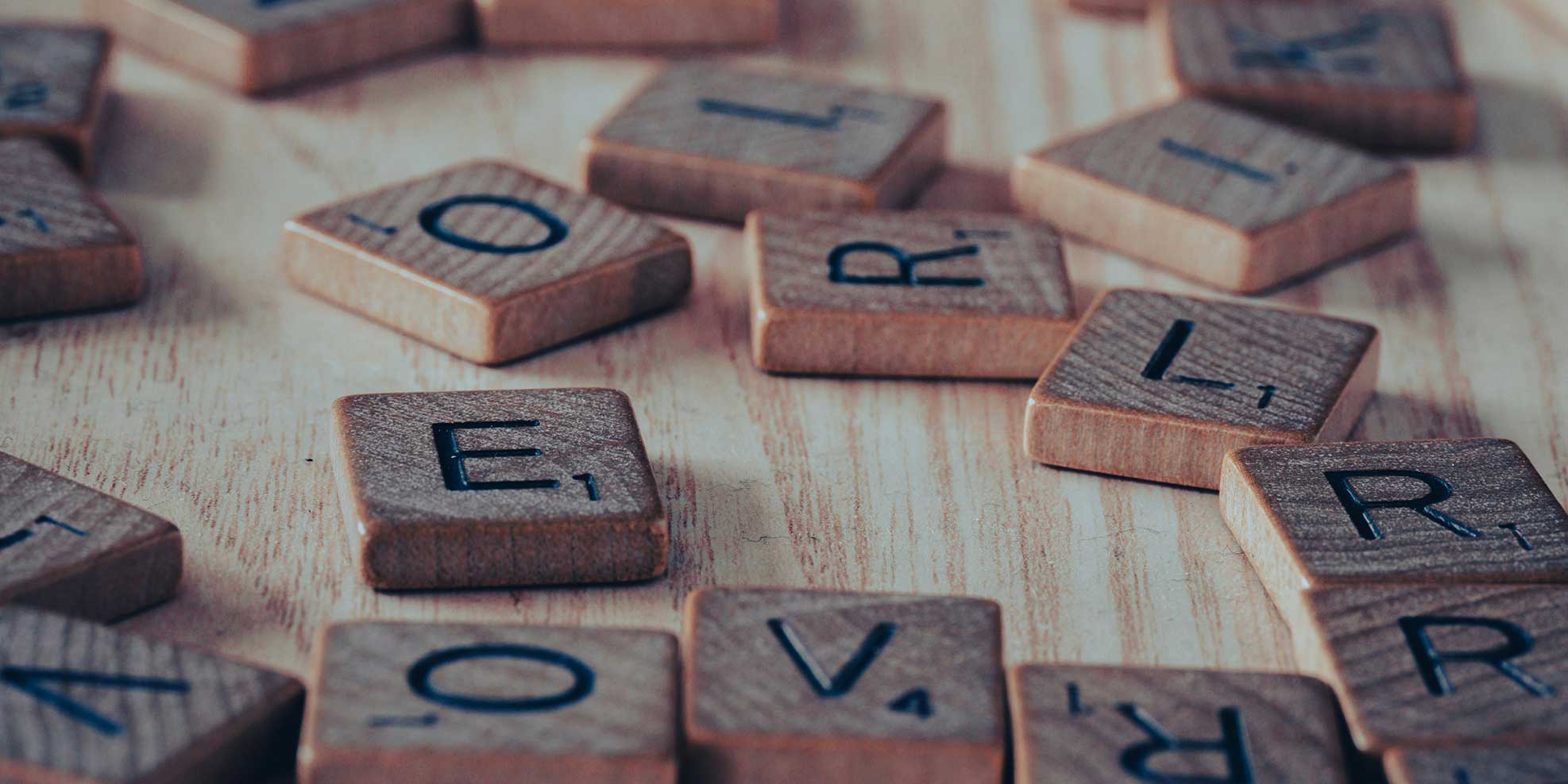 Scattered wooden letter tiles on a wooden table – symbolizing information and services from A to Z.