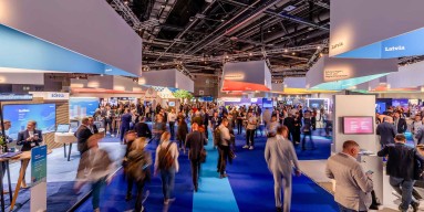 Lebhafter Messebereich auf der Smart Country Convention mit verschiedenen Ständen, Menschen in Anzügen und blauen Teppichen – eine energiegeladene und offene Atmosphäre zum Netzwerken.